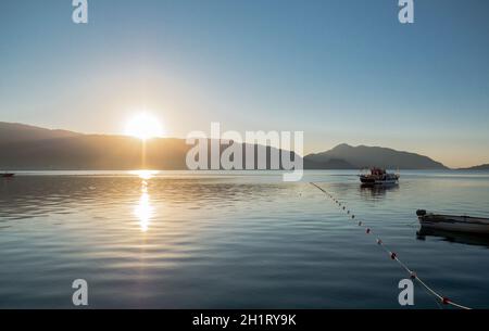 Spiaggia con edifici per gli hotel vicino alla baia con bianco barche e barche con palme verdi sullo sfondo di un cielo nuvoloso Foto Stock