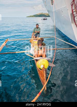 Hell-Ville, Madagascar - 19 Dicembre 2015 : malgascio fornitori da loro canoe outrigger offrono pesce e frutti tropicali di nave passeggeri presso Hell-Vill Foto Stock