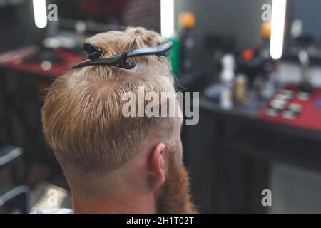 Servizio di parrucchiere. Processo di acconciatura dei capelli in un barbiere. Clip per capelli con un'acconciatura durante il taglio. Foto Stock