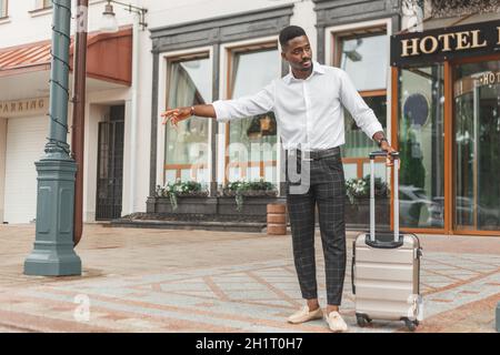 Giovane bell'uomo sul lato di una strada, salutando e fermandosi un taxi. Foto Stock