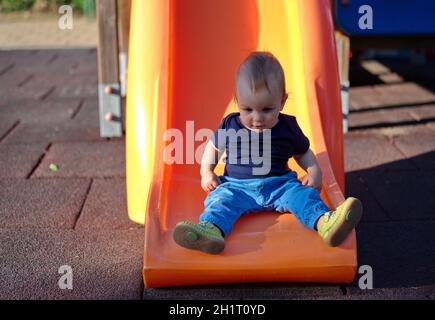 Bambino piccolo e carino seduto sullo toboga Foto Stock