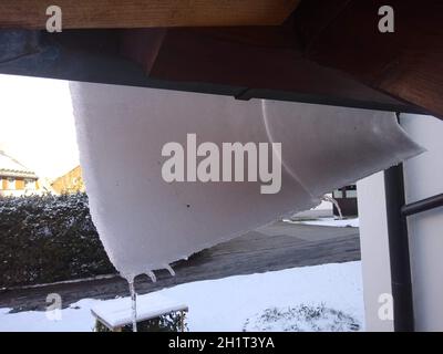 Bizzares Spiel der Natur beim comeback des Winters in der Nacht zum Mittwoch. Die Schnedecke eines Daches rutscht langsam über die Dachrinne Erst ab F Foto Stock