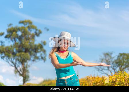 Donna brasiliana vestita in blu con una piantagione di soia. Stile di vita. Giovane ragazza con cappello in zona agricola. Paesaggio rurale. Donna sorridente in posa f Foto Stock