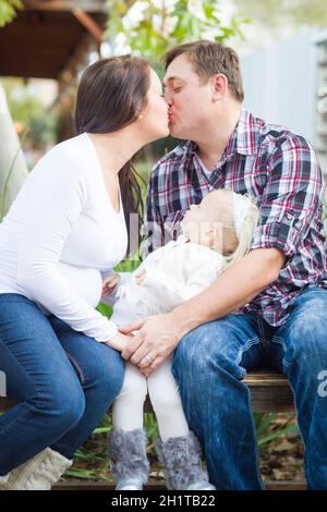 Felice coppia incinta baci al di fuori come bambina orologi. Foto Stock