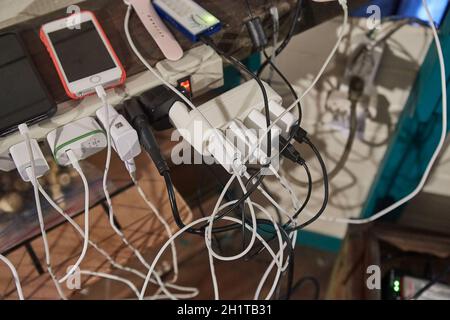 Nuqui, Choco, Colombia - circa 2019: Un sacco di caricabatterie per dispositivi aggrovigliati in un angolo affollato. L'elettricità è disponibile solo periodicamente nella villa Foto Stock