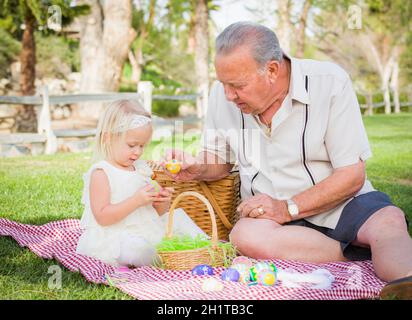 Amare il nonno e la nipote godendo le uova di Pasqua su una Coperta picnic al parco. Foto Stock