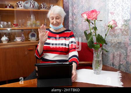 COVID-19 resta connesso. Donna anziana felice a casa videochiama la famiglia sul portatile o chattando online con gli amici a lunga distanza. Blocco del coronavirus Foto Stock