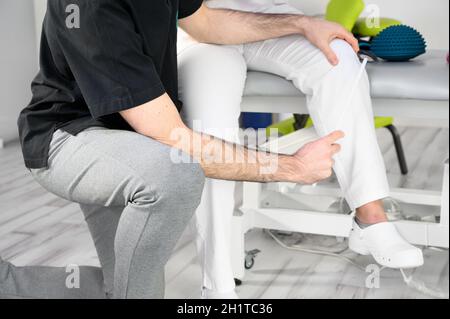 Esame neurologico. Il neurologo che esamina i riflessi su una paziente femminile con un martello. Foto di alta qualità Foto Stock