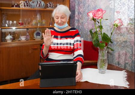 COVID-19 resta connesso. Donna anziana felice a casa videochiama la famiglia sul portatile o chattando online con gli amici a lunga distanza. Blocco del coronavirus Foto Stock