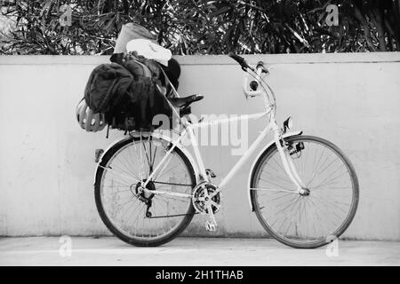 Scatto in scala di grigi di una bicicletta parcheggiata sulla strada contro un muro Foto Stock