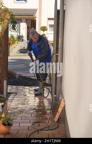 Operaio pulizia vialetto con benzina idropulitrice spruzzi la sporcizia, servizi di pulizia professionale.pulizia ad alta pressione, corpo inferiore. Foto Stock