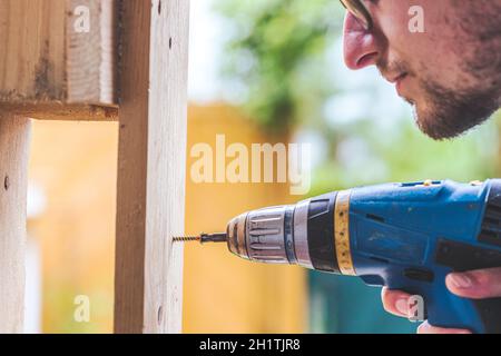 Fai da te l'handyman a casa sta usando un cacciavite cordless per l'avvitamento Foto Stock