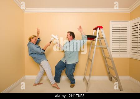 Divertimento giovane Riproduzione di spada lotta con i rulli di verniciatura in camera - scaletta e vassoio di vernice vicino a. Foto Stock