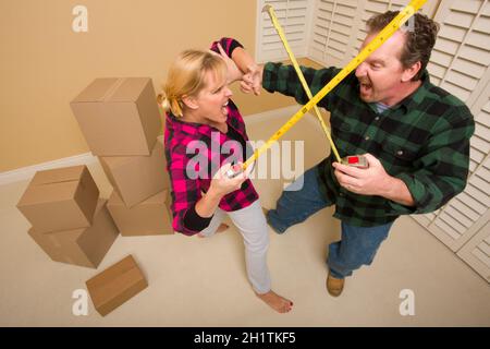 Coppia avente una spada divertente lotta con loro le misure lineari a nastro circondato da pranzo spostando le caselle. Foto Stock