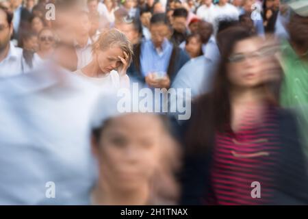 Folla di persone che camminano per la strada della città - immagine sfocata in movimento con volti irriconoscibili - giovane donna ferma, sentendosi giù, depresso Foto Stock
