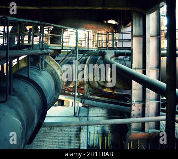 Vecchi interni di fabbrica abbandonati con molte tubazioni arrugginite. Grandi tubazioni arrugginite in fabbrica. Foto Stock