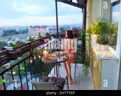 ragazza in abito rosa ha cena sul balcone Foto Stock