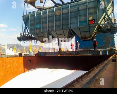 Novorossiysk, Russia - 10 Ottobre 2017: Carro della tramoggia di scarico su una nave da carico. Le operazioni di sollevamento nel porto. Foto Stock