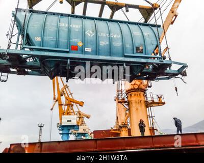 Novorossiysk, Russia - Agosto 11, 2017: spostamento ferrovia merci in auto la porta da una gru portuale. Il carico delle operazioni di sollevamento. Porto industriale. Foto Stock