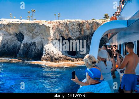 AYIA NAPA, CIPRO - 10 agosto 2019: Crociera in barca con i turisti vicino alle scogliere rocciose vicino Ayia Napa. Distretto di Famagosta, Cipro Foto Stock