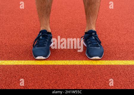 Inizia e sfida il concetto. Uomo in piedi dietro la linea gialla nel campo sportivo, preparatevi a muoversi in avanti o a cogliere la possibilità di successo. Foto Stock