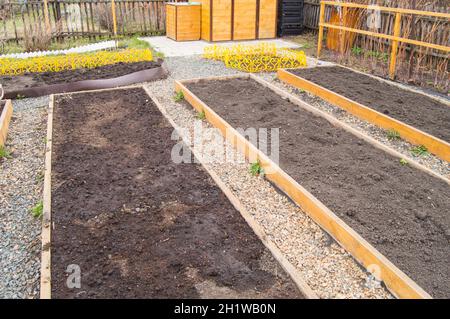 Letti di verdure rialzate di recente costruzione, letti vuoti con terreno preparato in giardino in primavera. Foto Stock