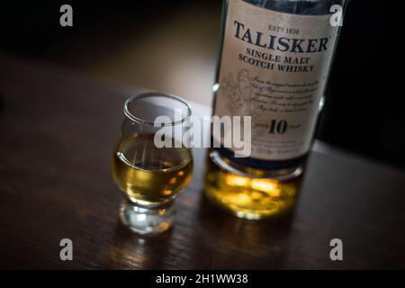 Bucarest, Romania - 5 agosto 2021: Immagine editoriale illustrativa di una singola bottiglia di whisky di scotch Talisker al malto accanto a un bicchiere sul bancone in un pub. Foto Stock