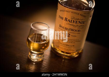 Bucarest, Romania - 5 agosto 2021: Immagine editoriale illustrativa di una singola bottiglia di whisky di scotch Balvenie al malto accanto a un bicchiere sul bancone in un pub. Foto Stock