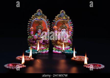 Eco-friendly Clay Morti o Moorti di Bhagwan Ganesha e la dea Mata Lakshmi Laxmi Devi. Argilla Diya Deep dia illuminata. Tema Festival per Diwali po Foto Stock