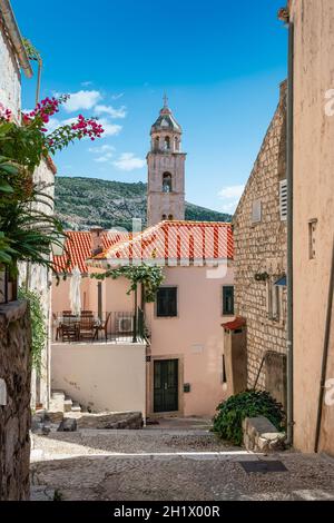 Torre dell'orologio dietro le case tradizionali in vicolo con scale nella città vecchia di Dubrovnik in Croazia. Foto Stock