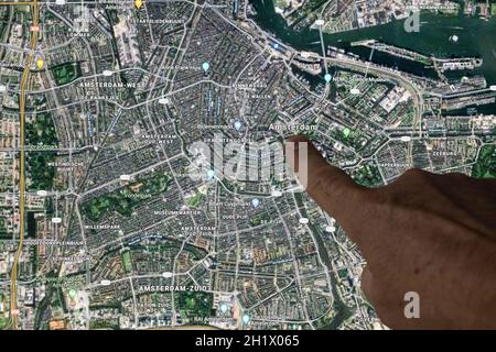 Udine, Italia. 21 agosto 2021. La vista satellitare di Gooble Maps di Amsterdam, capitale dei Paesi Bassi, indicata con un dito Foto Stock