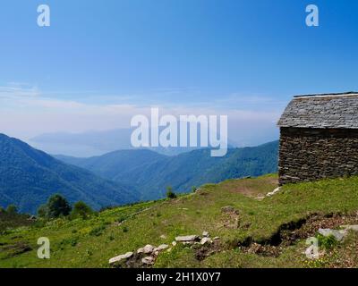 Tradizionale capanna in pietra a cima Sasso in Val Grande, parco nazionale piemontese. Vista panoramica sul Lago maggiore. Foto Stock