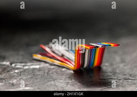 Primo piano di un cavo a nastro per computer corto, piegato e colorato su uno sfondo grigio con un gradiente verso la profondità di campo scura e poco profonda. Foto Stock