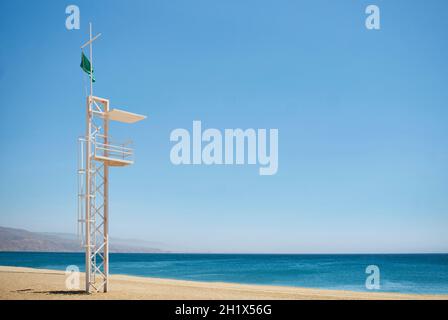 stazione di soccorso su una spiaggia con mare calmo in giorno di sole e bandiera verde Foto Stock