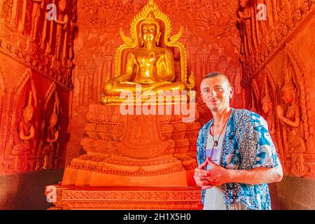 Giovane turista zaino in spalla nel tempio rosso Wat Sila Ngu Wat Ratchathammaram con buddha d'oro sull'isola di Koh Samui in Thailandia. Foto Stock