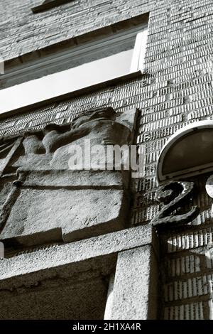 Un'immagine in bianco e nero. L'immagine è in una vista ad angolo basso di una vecchia facciata a muro di mattoni con ornamenti. Foto Stock