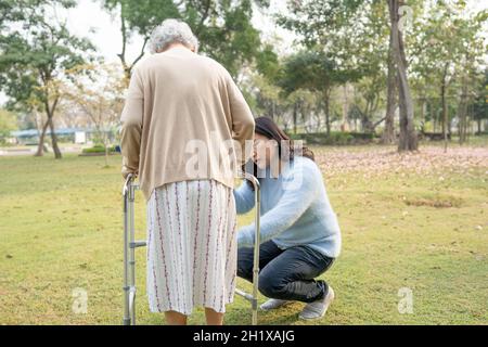 Aiuto e cura Asian anziani o anziani donna vecchia uso walker con forte salute mentre a piedi al parco in felice vacanza fresca. Foto Stock