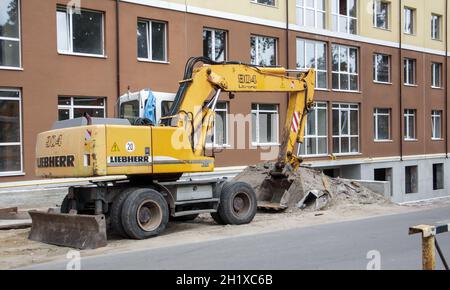 Gru caricatrice mobile di colore giallo sullo sfondo di un edificio in costruzione. Produttore internazionale di hardware. L'escavatore viene utilizzato per Foto Stock