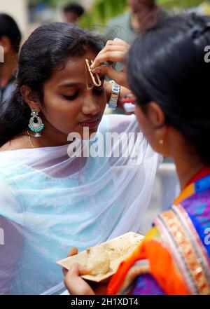 HYDERABAD,INDIA-AGOSTO 24,2019: Donna indù indiana applicare Tilak su testa anteriore di un devotee, un rituale religioso, sulla celebrazione del festival di Krisnastami in Dio Foto Stock