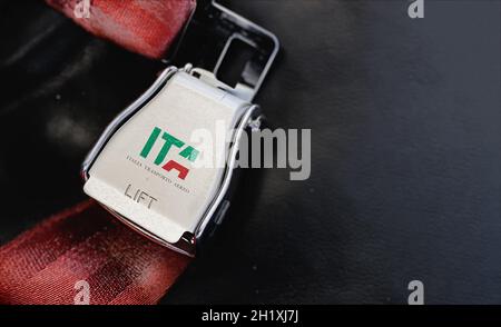 Roma, Italia, luglio 2021: Cintura di sicurezza rossa di un sedile vuoto all'interno di un aeroplano con il logo ITA stampato sul metallo. ITA è il nuovo vettore di bandiera italiano s. Foto Stock