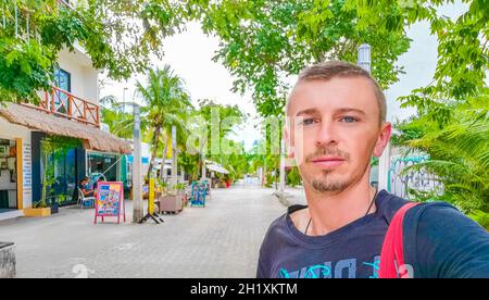 Viaggiatore di turismo russo maschile a strada tipica e paesaggio urbano la Quinta Avenida con negozi e la costruzione di Playa del Carmen in Messico. Foto Stock