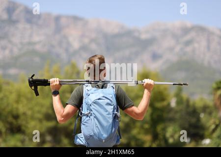 L'escursionista è in possesso di bastoni finlandesi per camminare fino alla cima della montagna Foto Stock