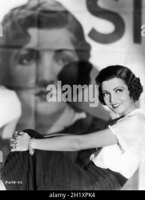 CLAUDETTE COLBERT Ritratto di fronte a un grande poster cinematografico per la SUA CANTANTE DI CANNELLI 1933 registi ALEXANDER HALL e GEORGE SOMNES Costume design Travis Banton Paramount Pictures Foto Stock
