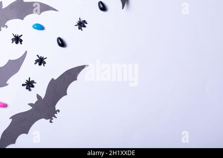 Composizione di decorazioni di Halloween con ragni, pipistrelli e dolci su sfondo bianco Foto Stock