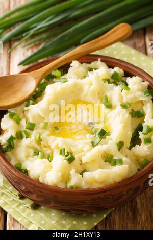 Il Champ è un piatto irlandese di purè di patate con scallioni, burro e latte in primo piano nella ciotola sul tavolo. Verticale Foto Stock