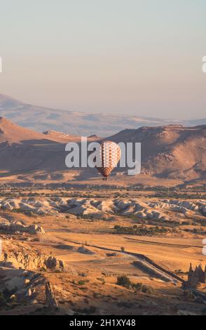 Paesaggio con mongolfiera mongolfiera a scacchi che si innalza sul panorama della valle Cappadocia nella luce del mattino Foto Stock