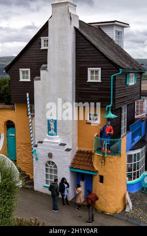 Portmeirion villaggio, Gwynedd, Galles del Nord - turisti visitatori che guardano Toll House con la statua di San Pietro predicazione - villaggio turistico Foto Stock