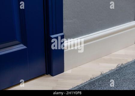 Porta in legno blu e adiacente alto pavimento classico plinth. Elementi di arredo interno. Foto Stock