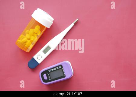 pulsossimetro, pillole mediche e termometro su sfondo colorato Foto Stock
