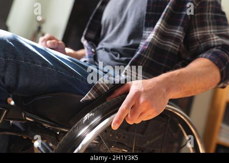 Parte centrale di uomo disabile caucasico seduto su sedia a rotelle a casa Foto Stock
